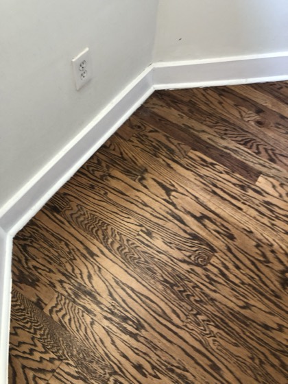 Dark-stained hardwood meeting crisp white baseboard — AttarCo Homes roofing & remodeling project, Houston TX
