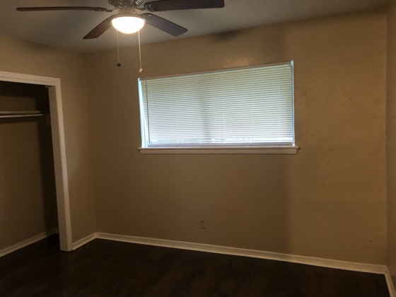 Finished bedroom with new dark wood floors and ceiling fan — AttarCo Homes roofing & remodeling project, Houston TX