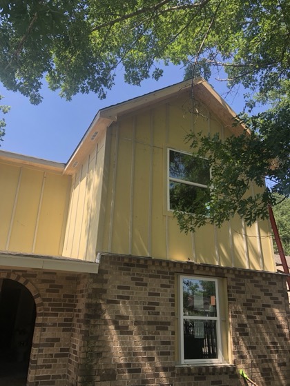 Fresh siding and brick base framed by trees — AttarCo Homes roofing & remodeling project, Houston TX