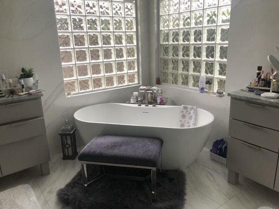 Marble bathroom with freestanding tub and glass-block windows — AttarCo Homes roofing & remodeling project, Houston TX