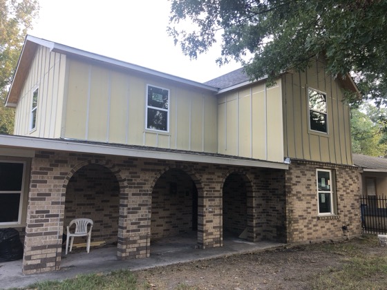Rear elevation with new board-and-batten siding over brick arches — AttarCo Homes roofing & remodeling project, Houston TX