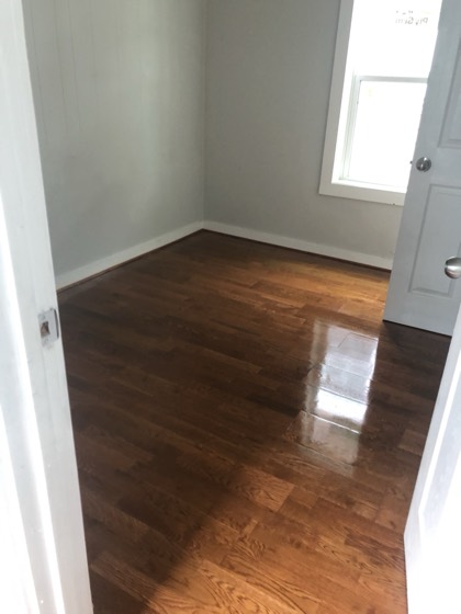 Refinished glossy hardwood floors in bright room — AttarCo Homes roofing & remodeling project, Houston TX