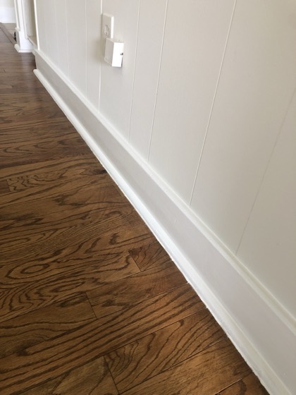Refinished hardwood floor with fresh white trim and paneling — AttarCo Homes roofing & remodeling project, Houston TX