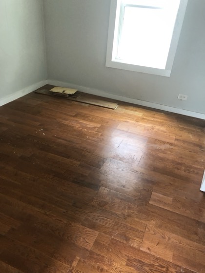 Refinished warm hardwood floor in bright room — AttarCo Homes roofing & remodeling project, Houston TX