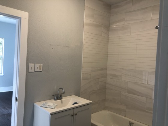 Renovated bathroom with tiled tub surround and new vanity — AttarCo Homes roofing & remodeling project, Houston TX