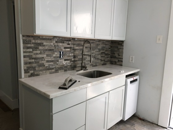Renovated kitchen with marble counter and stone backsplash — AttarCo Homes roofing & remodeling project, Houston TX