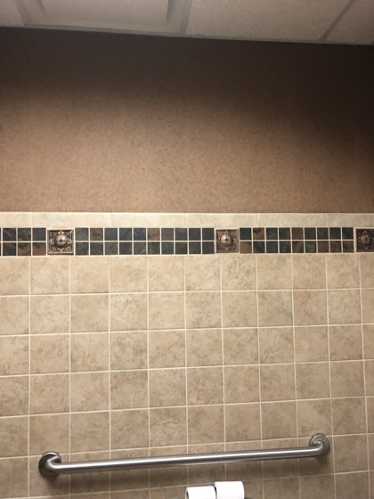 Tiled bathroom wall with decorative accent band — AttarCo Homes roofing & remodeling project, Houston TX