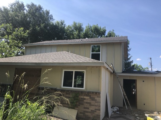 Two-story exterior mid-renovation with new roof and siding — AttarCo Homes roofing & remodeling project, Houston TX